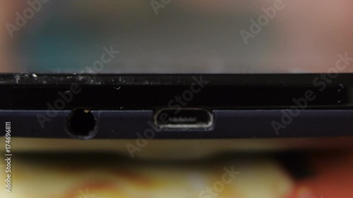 White hand plugs out micro usb cable from cell phone