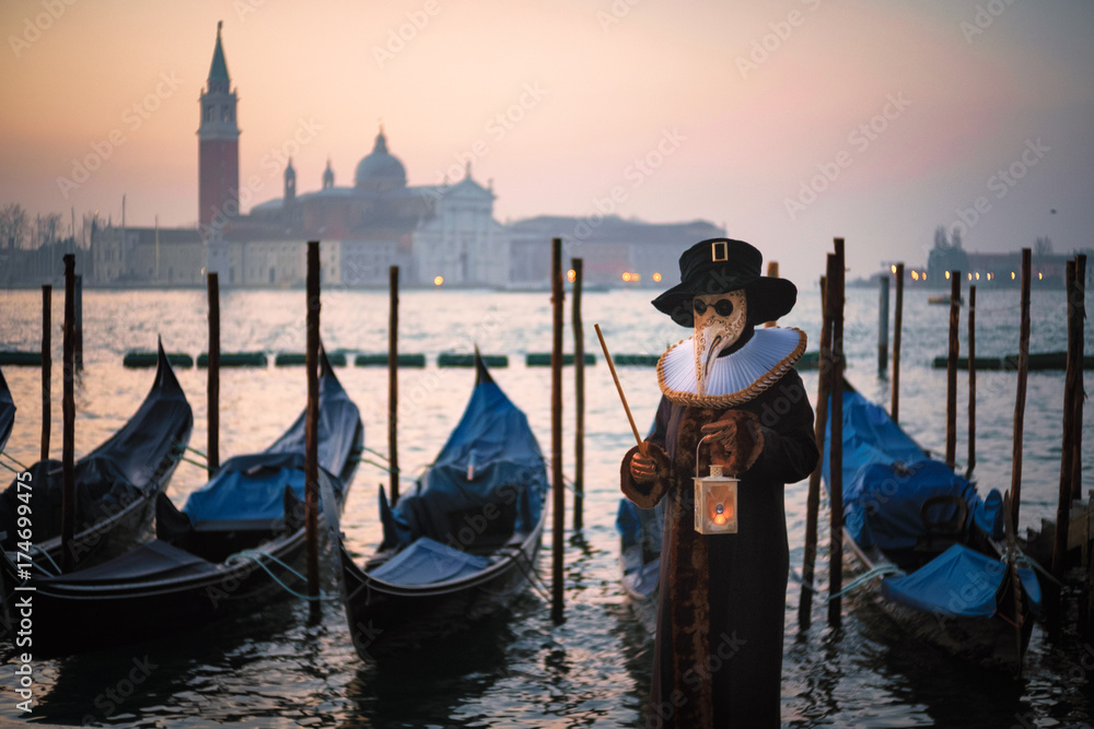 Man in Carnival costume with gondolas on Grand Canal against San Giorgio Maggiore church