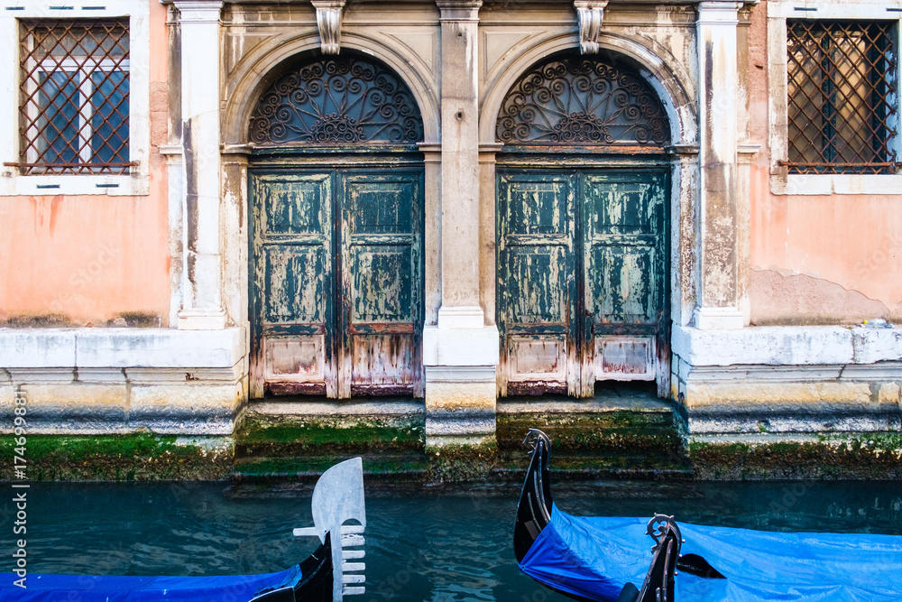 The parked gondolas in small back channel, Venice. Old weathered door.