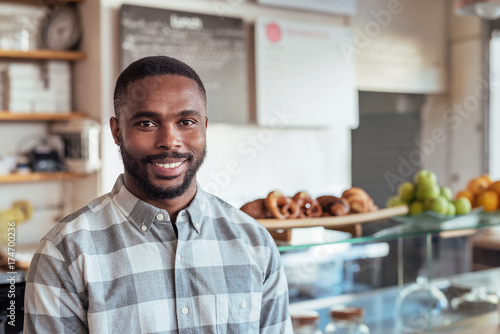 Smiling young African entrepreneur standing in his cafe