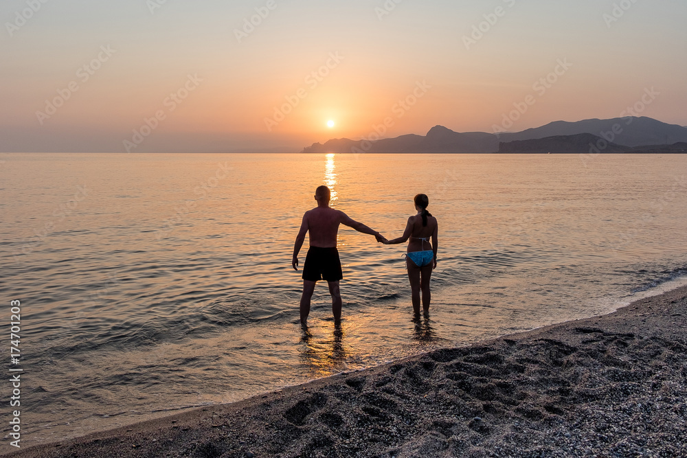 Lovers holding hands at sunset at sea