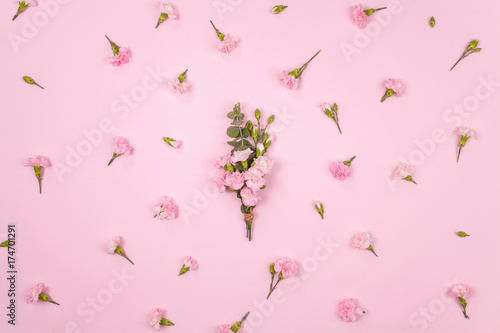 Carnation bouquet with floral pattern made of pink carnation flowers on pink background. Flat lay, top view. Wedding background.
