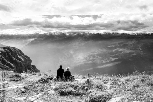 Two trekking people  sitting on the Swiss Alps Chaeserrugg, Toggenburg, enjoying the dramatic clouds moment photo