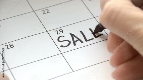 Writing SALE on calendar with a black marker