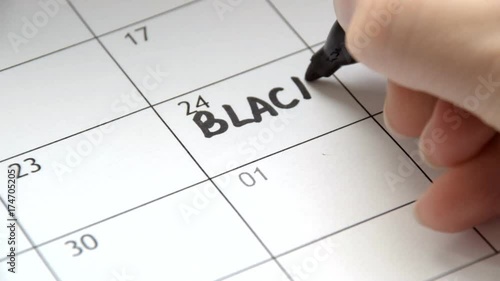 Writing BLACK FRIDAY on calendar with a black marker