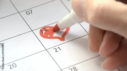 Writing RED HEART on 14th February on calendar with a red marker