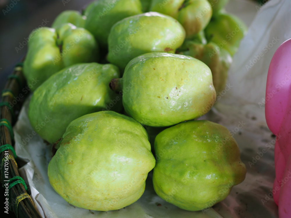 Green fresh guava piled up on flat wide basket, from Thai local street food market stall Green fresh guava piled up on flat wide basket, from Thai local street food market stall