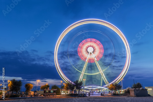 Spinning ferris wheel at sunrise blue hour in Rimini  Italy. Long exposure abstract image