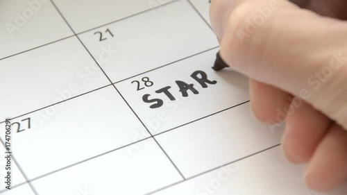Writing START COLLEGE on calendar with a black marker