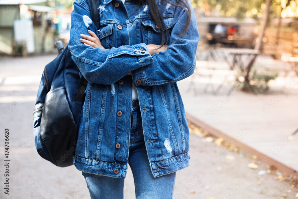 Fashionable young woman in jeans, long jeans jacket and handbag on the city streets. Fashion.Stylish . Fashionable young woman in jeans, long jeans jacket and handbag on the city streets. Fashion.Stylish .