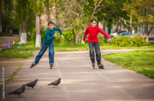 Three children on in line skates in park © liandstudio