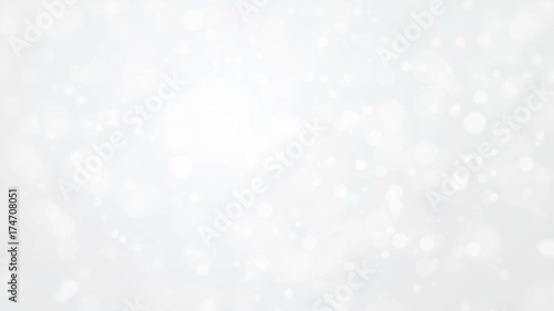 Glowing abstract holiday background with bokeh lights flickering on silver white backdrop.