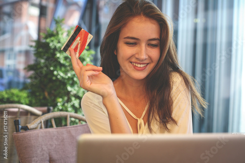 Photos Young woman using lap top and credit card.