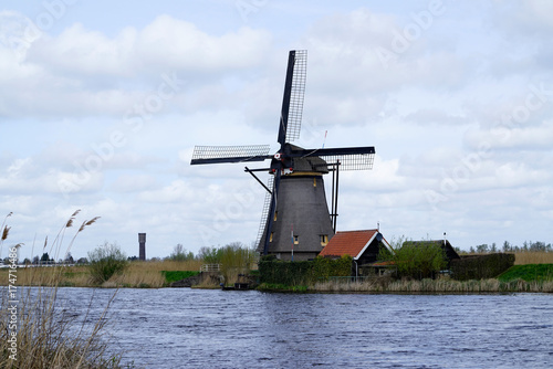 Dutch windmill in the afternoon build and standing next to polder water in kinderdijk south holland used to drain water out by using wind power and keep land dry.