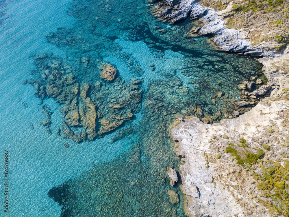 Vista aerea di scogli sul mare. Costa della Corsica, scogliera e panoramica del fondo marino visto dall’alto, acqua trasparente. Penisola di Cap Corse. Francia