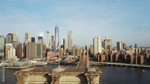 Aerial view of Brooklyn bridge with American flag waving on the wind. Scenic view of East river, Manhattan in New York.