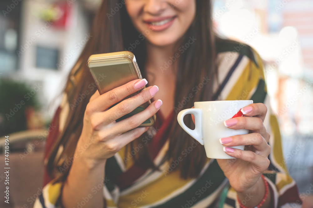 Happy woman using smart phone and holding cup of coffee. Close up. Happy woman using smart phone and holding cup of coffee. Close up.