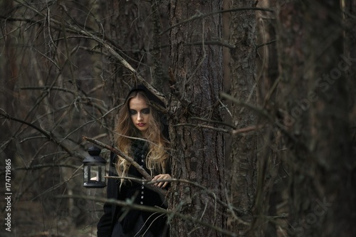 Halloween. beautiful girl in a black dress in the forest