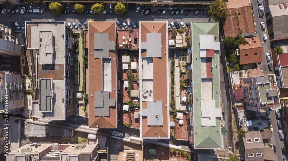 Vista aerea perpendicolare dei tetti di alti palazzi adibiti ad uso residenziale in una grande città italiana. Le automobili e le persone dall'alto sembrano molto piccoli.