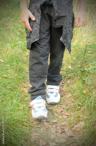 A boy walking in a hike in sneakers and a backpack behind his shoulders.
