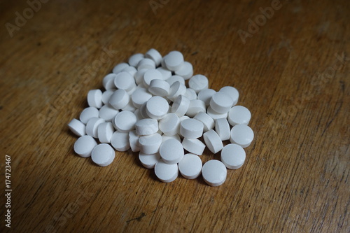 Handful of pure white pills on wood