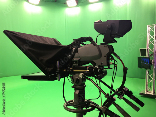 Modern empty green video recording and broadcasting studio with tv channel led screen and metalic stands, text prompter, lights on