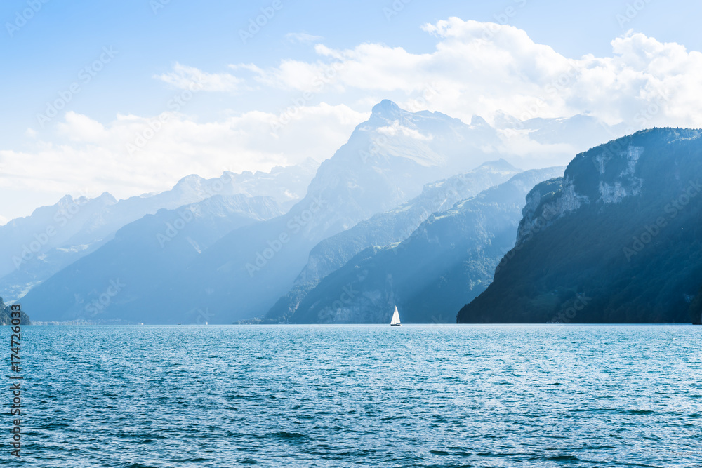 Halftone light and shadow in the mountains. Mountain range. Swiss Alps. Lake Lucerne. White sail on the lake. 