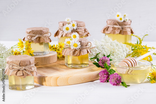 Honey in a jar  flowers and honey dipper on white background