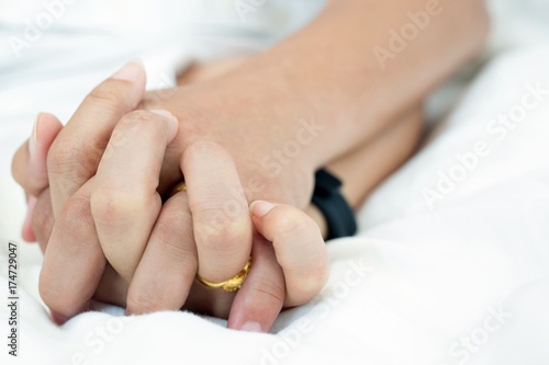  Hands of couple lovers on a bed at honeymoon with lust and love. Concept about love, sex and lifestyle.
