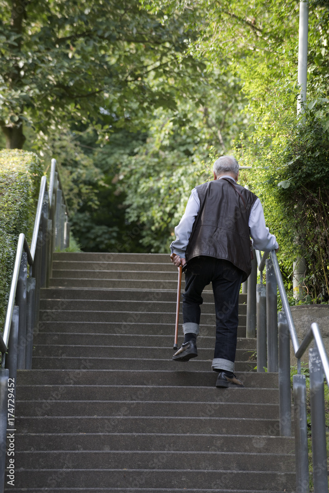 alter Mann geht am Stock eine Treppe hinauf