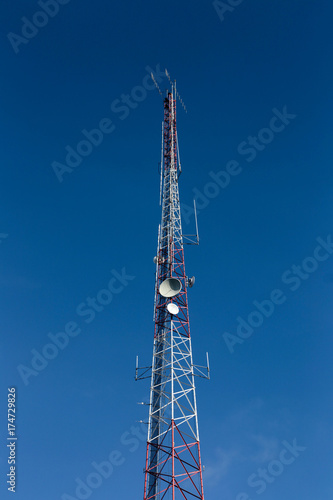 High antenna tower used for various signals and blue sky in background.
