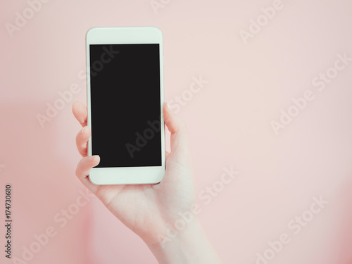 hold and show smart phone by asian woman beauty right hand with pink pastel background
