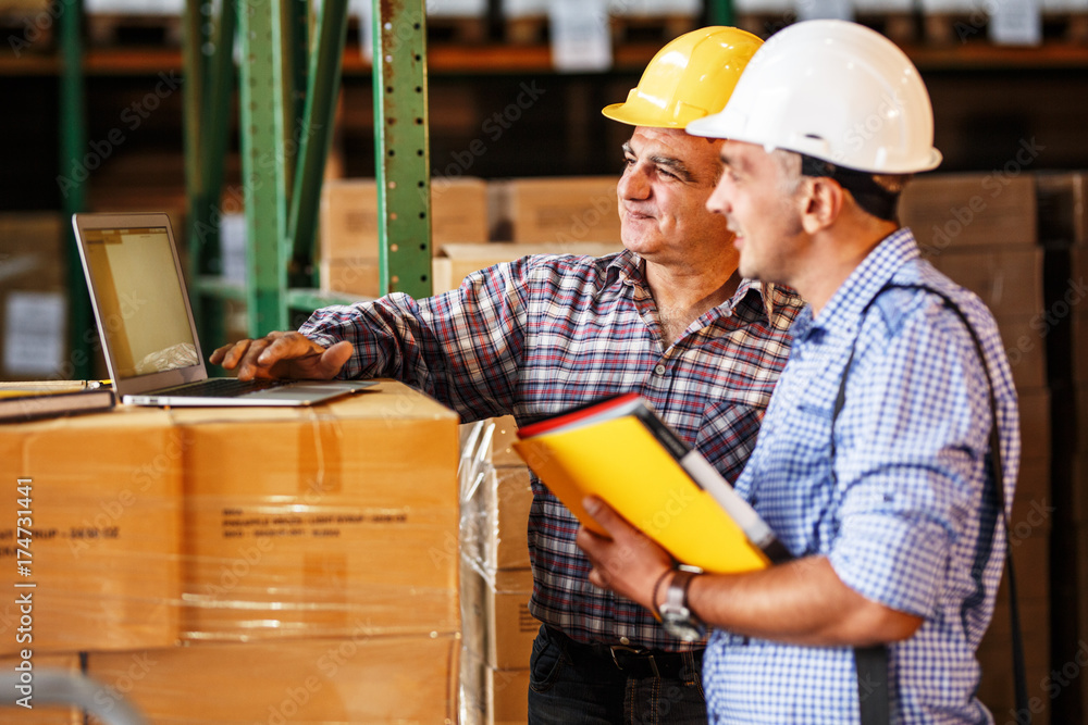 Male manager and warehouse worker checking list and inventory on laptop.Customs. Male manager and warehouse worker checking list and inventory on laptop.Customs.