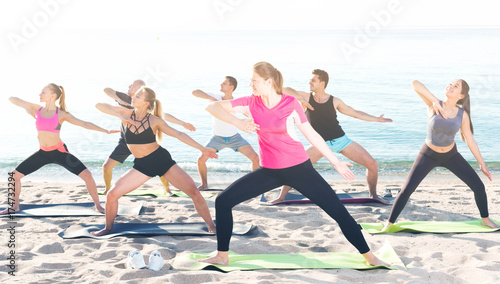 People practicing yoga on beach