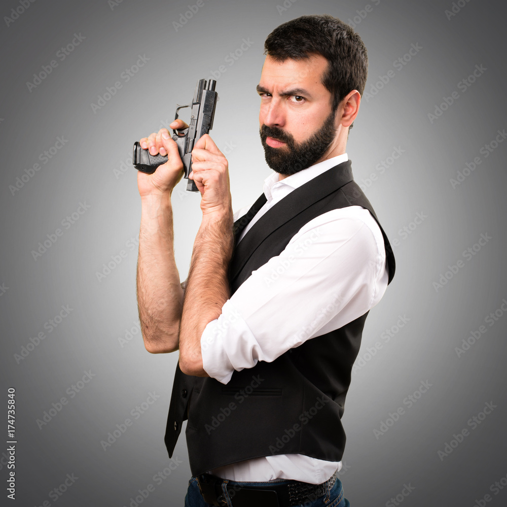 Cool man holding a pistol on grey background Cool man holding a pistol on grey background