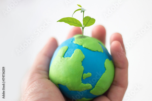 concept of earth day , hand holding earth with small plant