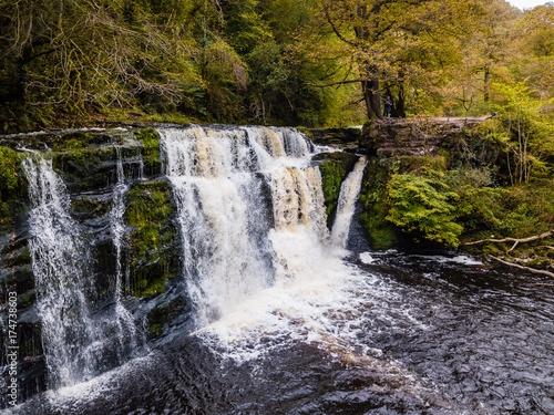 A picturesque waterfall  Sgwd Y Pannwr  in a tree lined river valley during the autumn