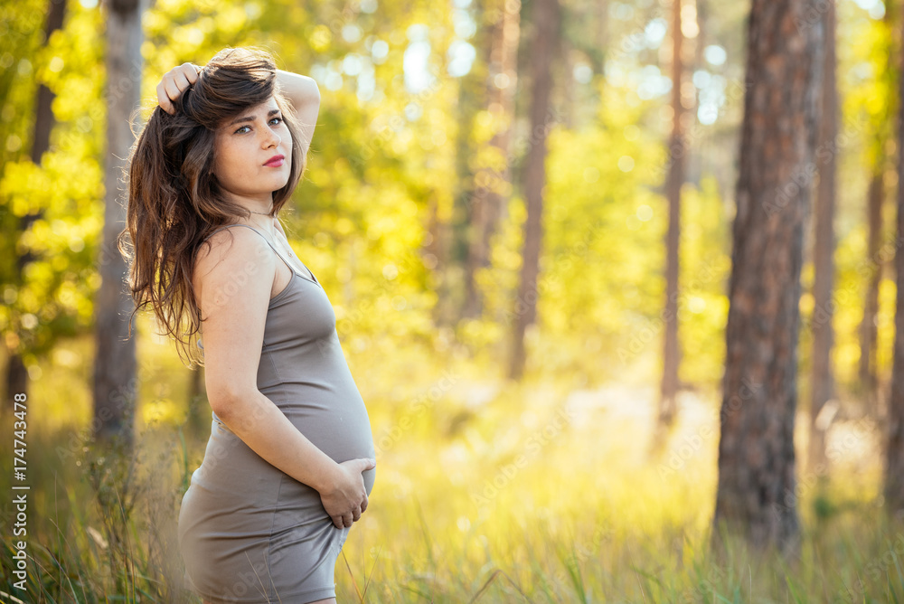 portrait of a beautiful young pregnant girl in a trendy dress against the background of an autumn forest portrait of a beautiful young pregnant girl in a trendy dress against the background of an autumn forest