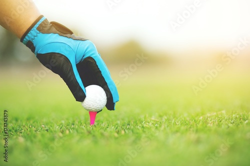 Close up of Hand putting golf ball on tee in golf course on atmosphere Light sunshine.