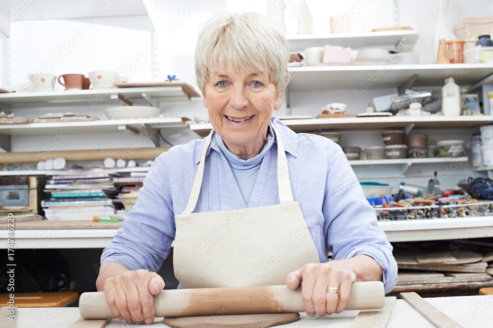 Portrait Of Senior Woman Rolling Out Clay In Pottery Studio Portrait Of Senior Woman Rolling Out Clay In Pottery Studio