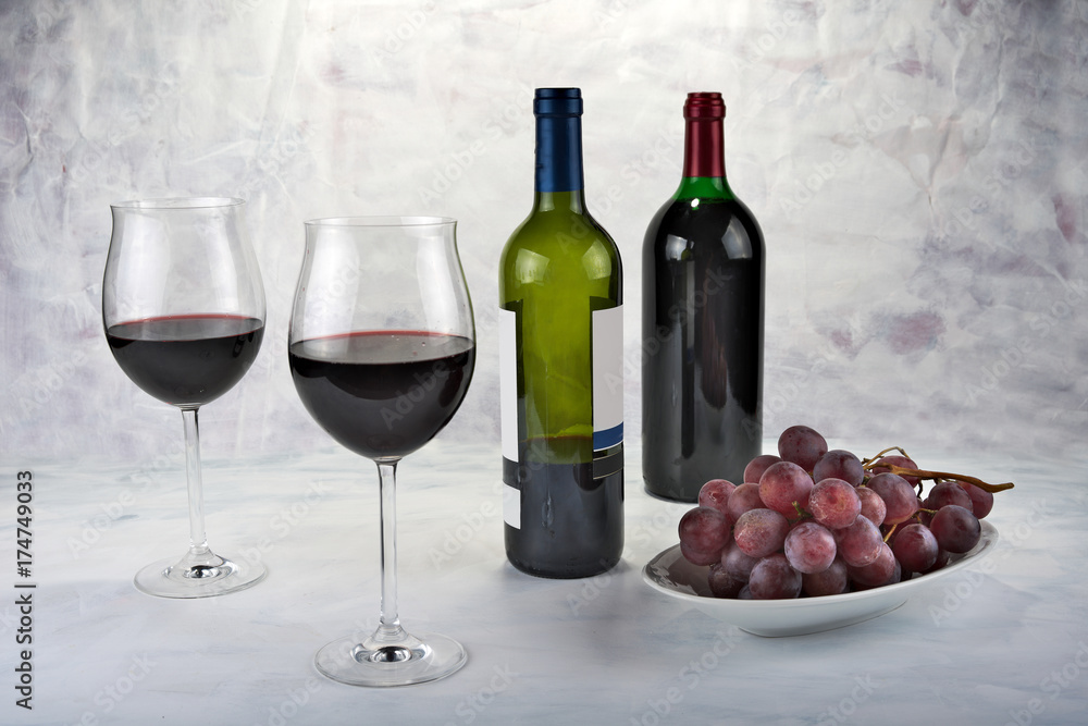 Two glasses of red wine with bottle and grapes