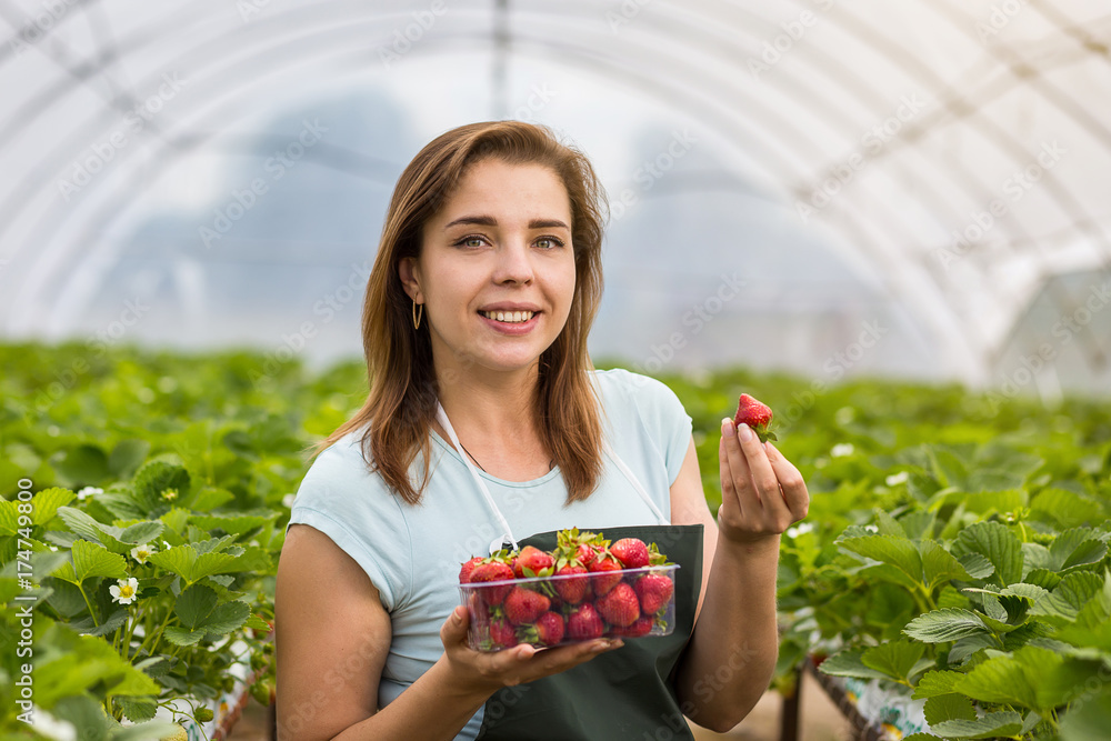 Φωτογραφία Woman holding a juicy bitten strawberry into the camera,strawberry in arm