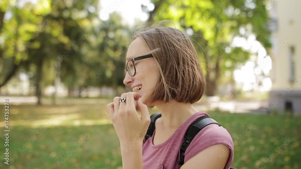 Young pretty girl in eyeglasses smiles happily into camera, close up. Wonderful smiling woman with a lovely look and natural make up looking at camera and the wind moving her hair. Young pretty girl in eyeglasses smiles happily into camera, close up. Wonderful smiling woman with a lovely look and natural make up looking at camera and the wind moving her hair.