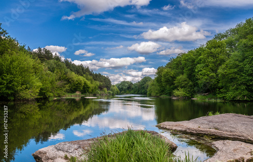 Summer landscape of the river  blue sky with clouds  reflections in the water  woods and stones. The river Ros  Ukraine.