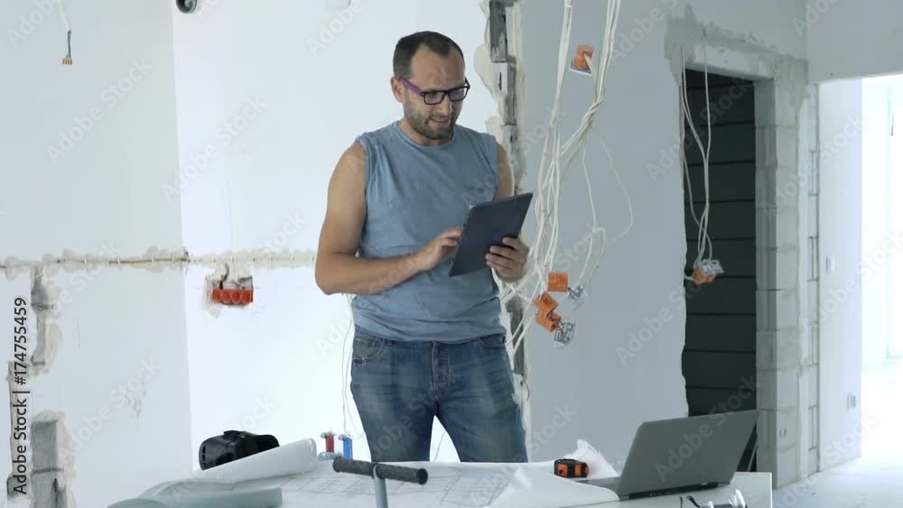 Young man checking project on tablet computer standing by table at new home
Young man checking project on tablet computer standing by table at new home