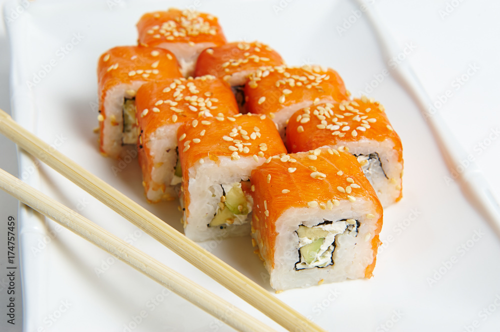Philadelphia rolls on a white plate with chopsticks. with salmon, shrimp, avocado, cream cheese. Sushi menu. Japanese food. Philadelphia rolls on a white plate with chopsticks. with salmon, shrimp, avocado, cream cheese. Sushi menu. Japanese food.