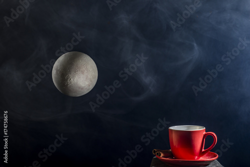 A cup of coffee and a full moon on a dark background