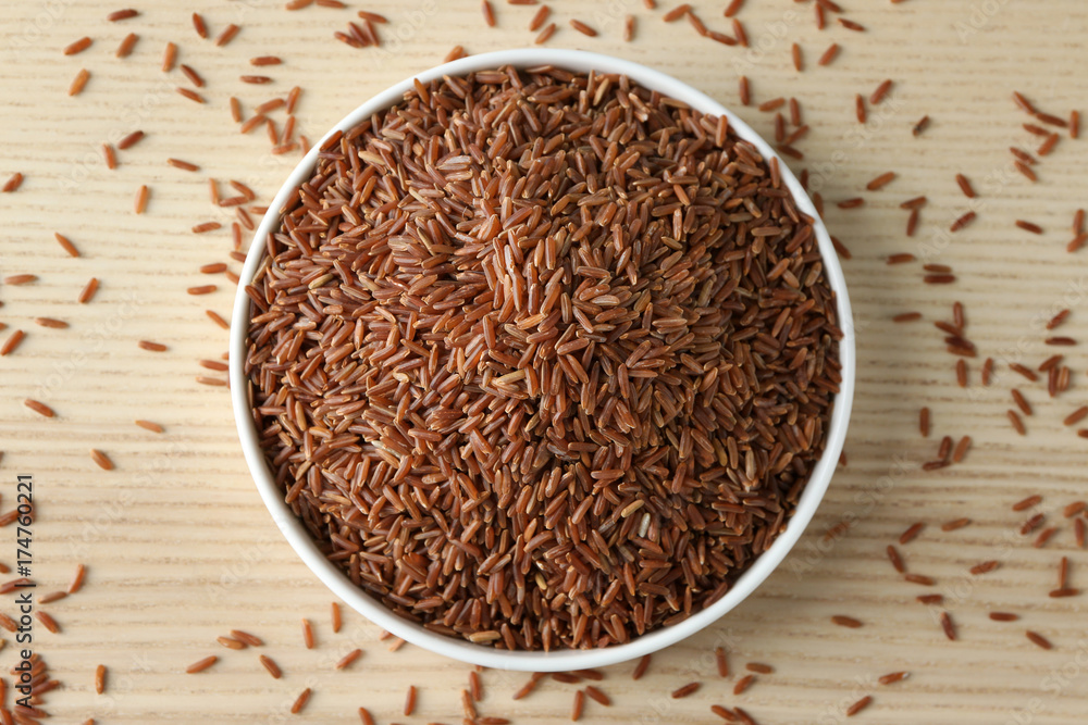Bowl with raw red Cargo rice on wooden background Bowl with raw red Cargo rice on wooden background