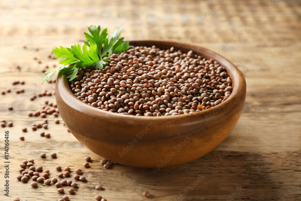 Bowl with brown lentils on wooden background Bowl with brown lentils on wooden background