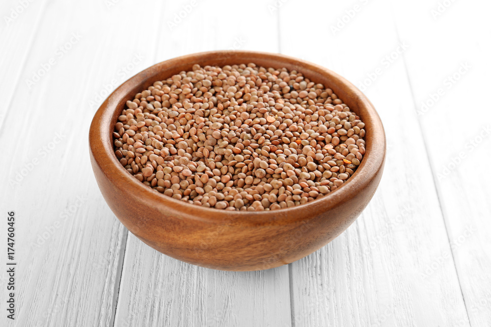 Bowl with brown lentils on wooden background Bowl with brown lentils on wooden background